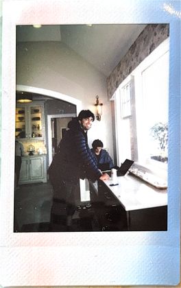 A teammate leaning on a counter by the window, laptop open