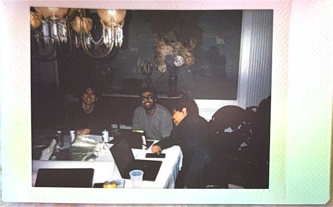 The team hacking around a dining table under a chandelier